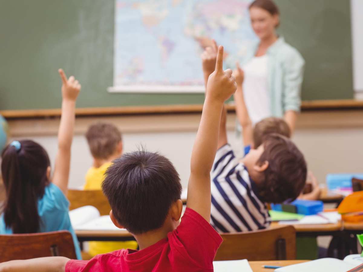 Pupils raising hand during geography lesson in classroom at the elementary school